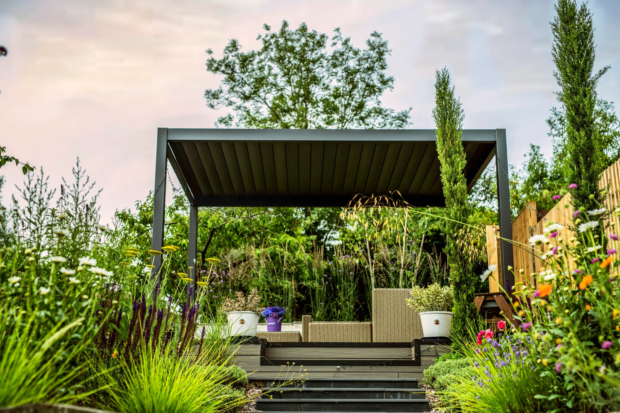 The steel pergola with its rattan seating, framed by slim cypresses, lavender and grasses