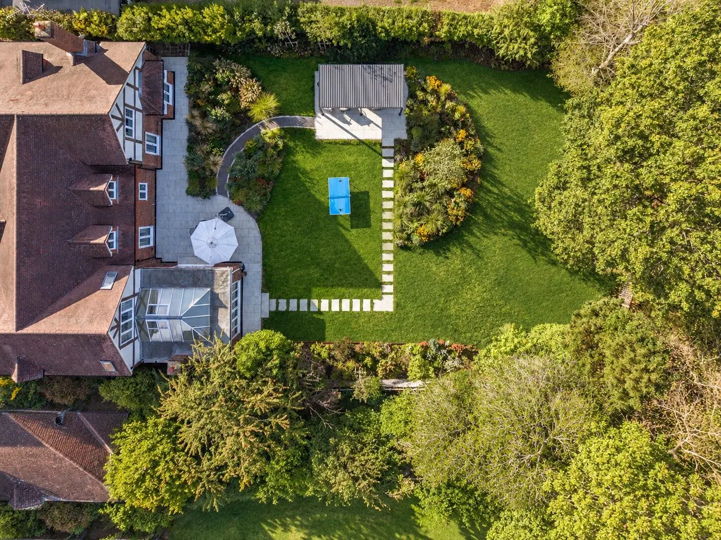The garden from above: the terrace and orangery, the curved border, the lawn with a table-tennis table, the stepping stones and the pergola