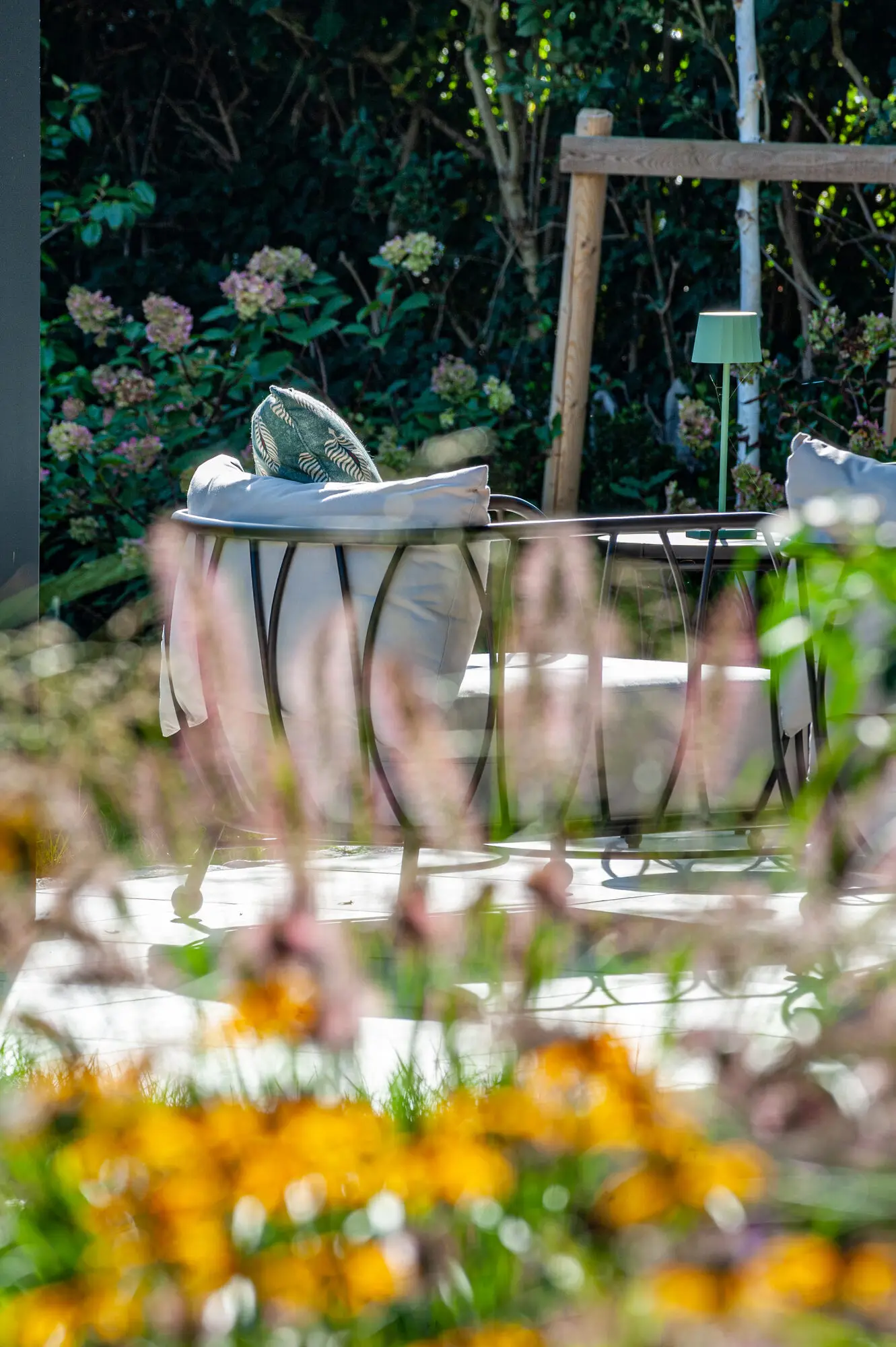 Lounge seating under the pergola seen across rudbeckia and roses