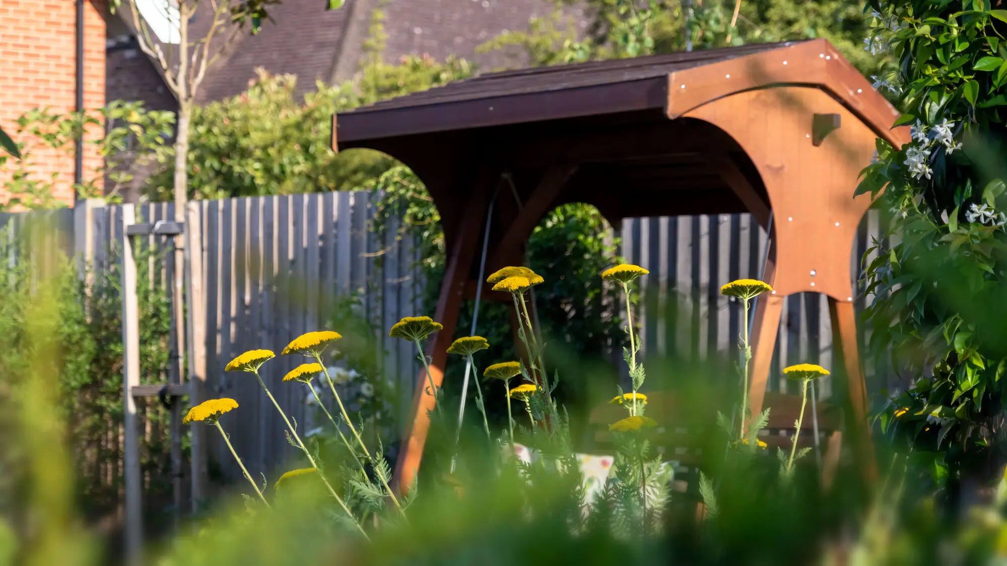 The corten steel swing seat rising above yellow achillea and grasses