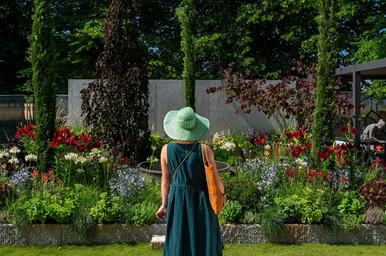 The ILLUSION 2050 courtyard garden at RHS Hampton Court 2025, with red lilies, alliums and eryngium through the planting