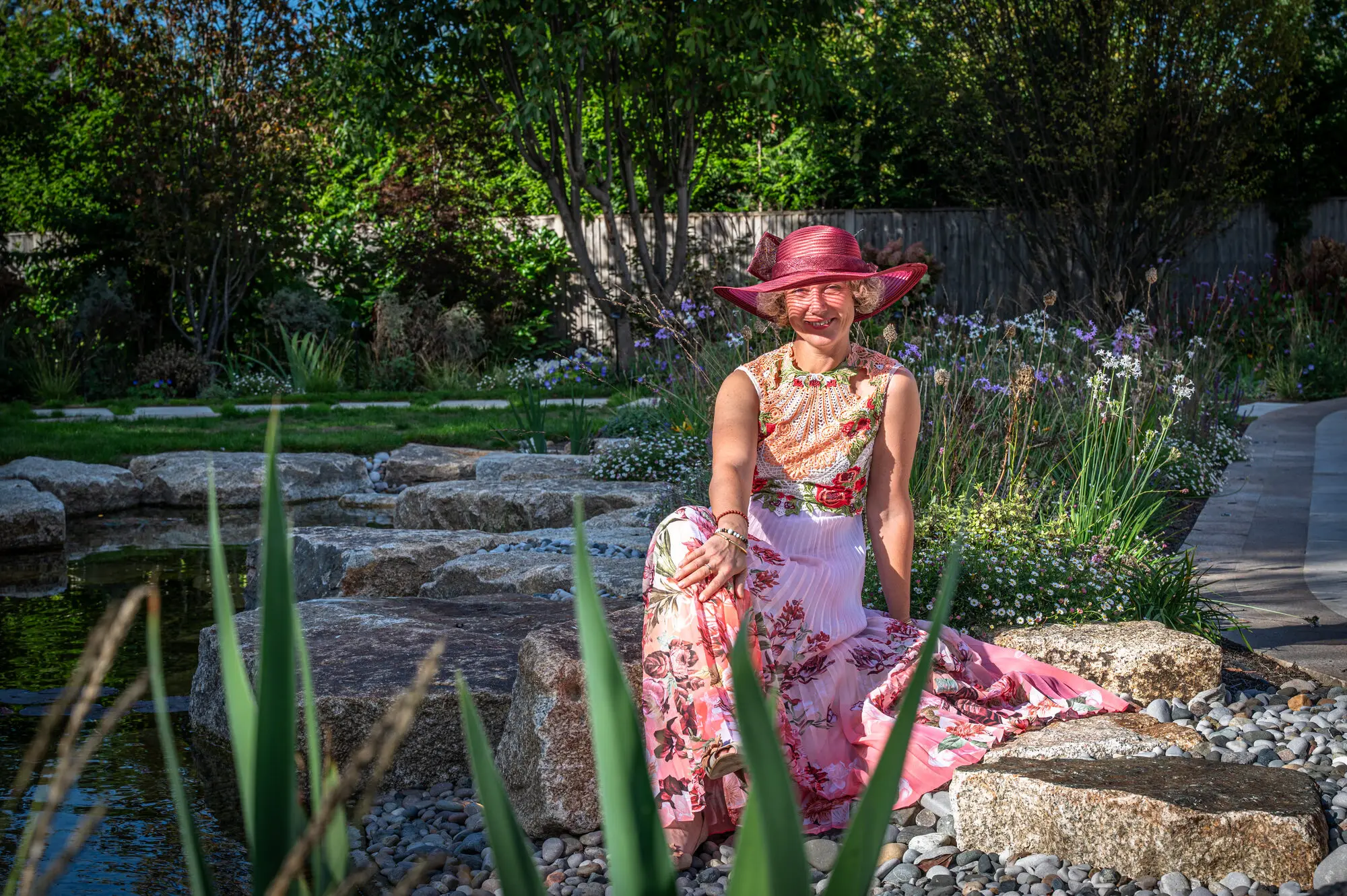 Kitti Kovacs sitting on a granite slab beside the ponds of the garden