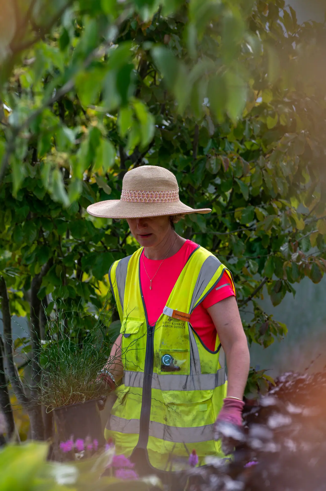 Kitti Kovacs in a hi-vis vest and sun hat, building the show garden