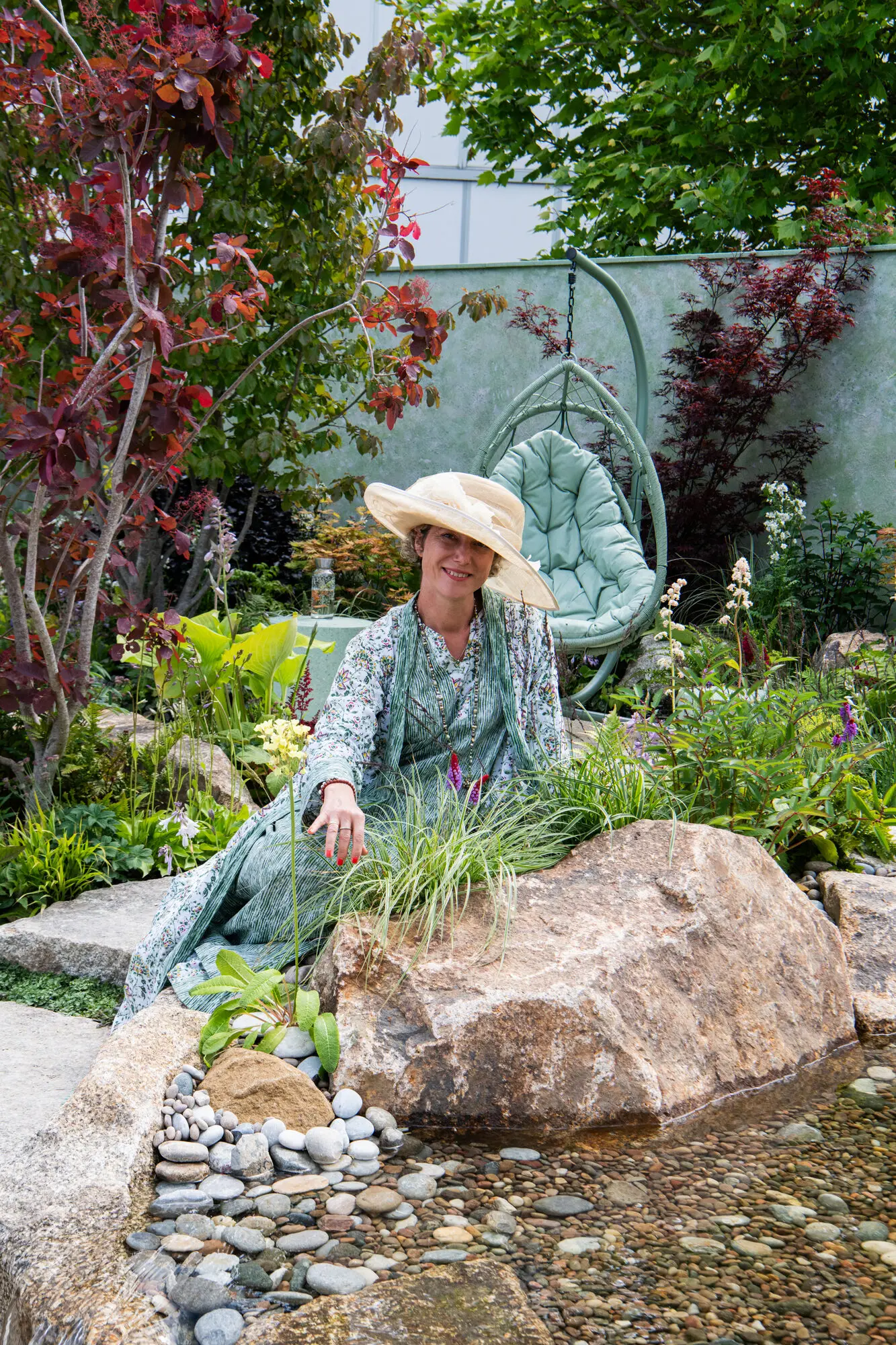 Kitti Kovacs beside a naturalistic water feature in a Water and Wellbeing Garden