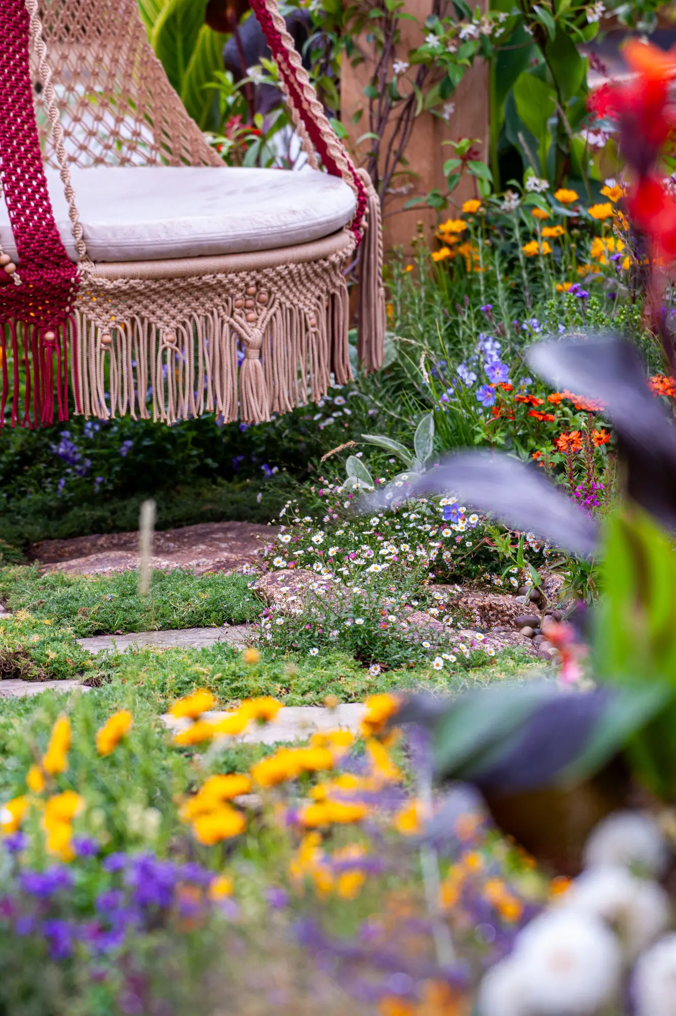 Handmade macramé swing surrounded by colourful layered planting in the 100 Sweet Summers show garden
