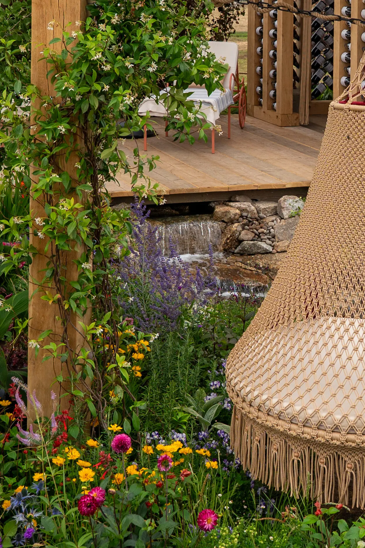 Handmade macramé swing surrounded by colourful planting and a naturalistic waterfall