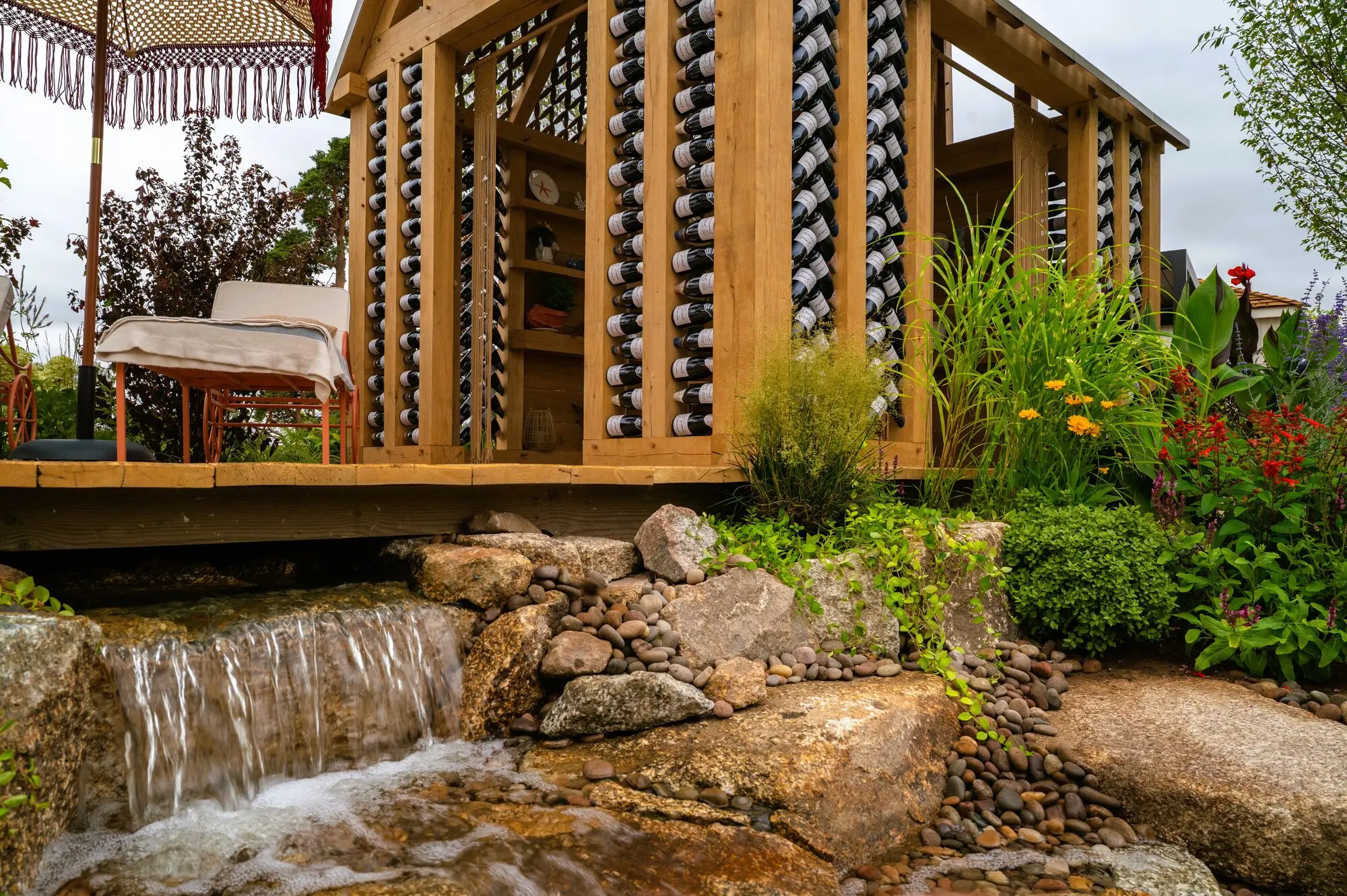 Naturalistic waterfall surrounded by colourful planting and natural stone in the 100 Sweet Summers show garden