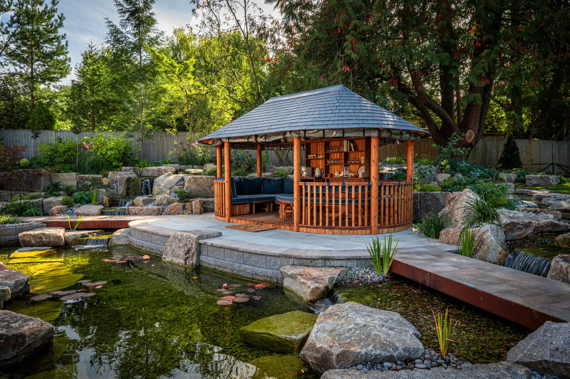 The Breeze House on its granite-edged island, with a corten bridge over the pond