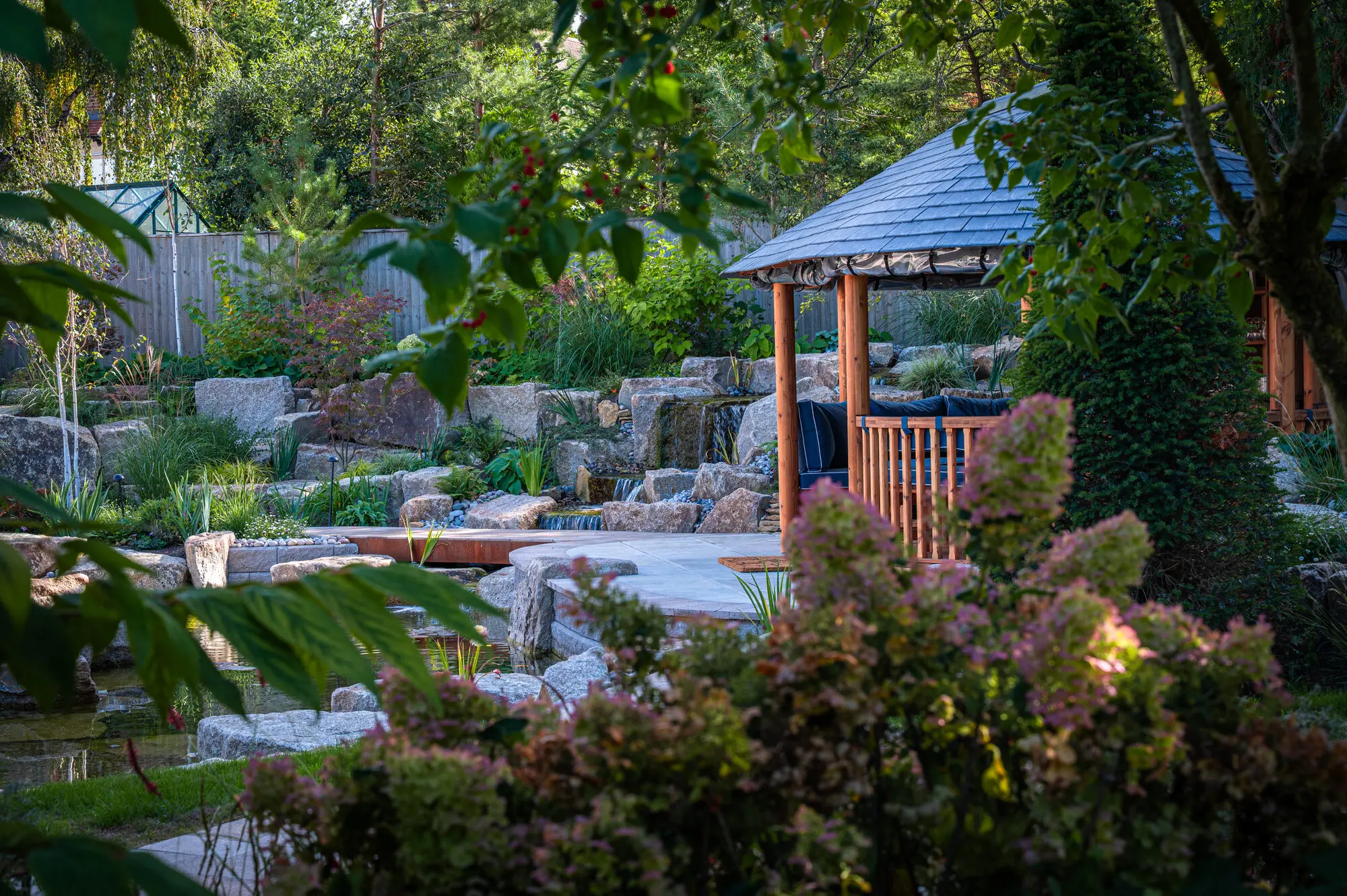 Pink hydrangeas and layered planting in front of the granite ponds and the Breeze House